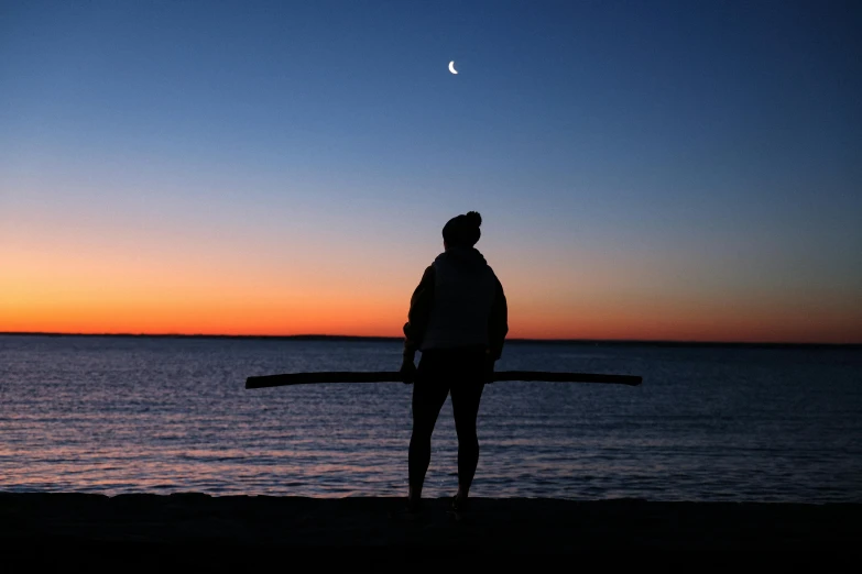 the woman is standing on a beach holding a board