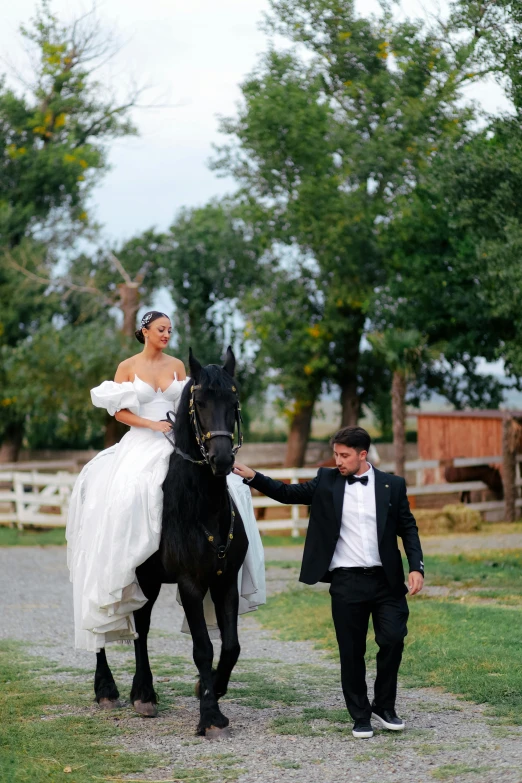 a young woman in a wedding dress riding a black horse