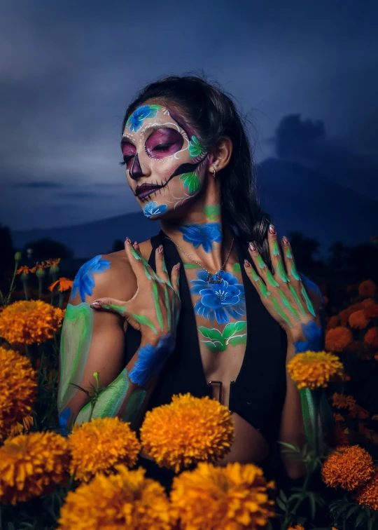 woman with painted face sitting in flowers and smiling