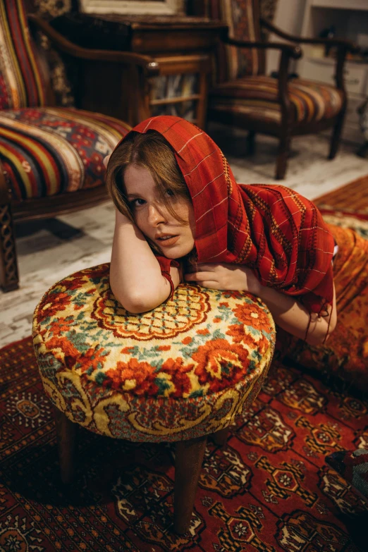 a woman is sitting on the floor wearing a red headdress