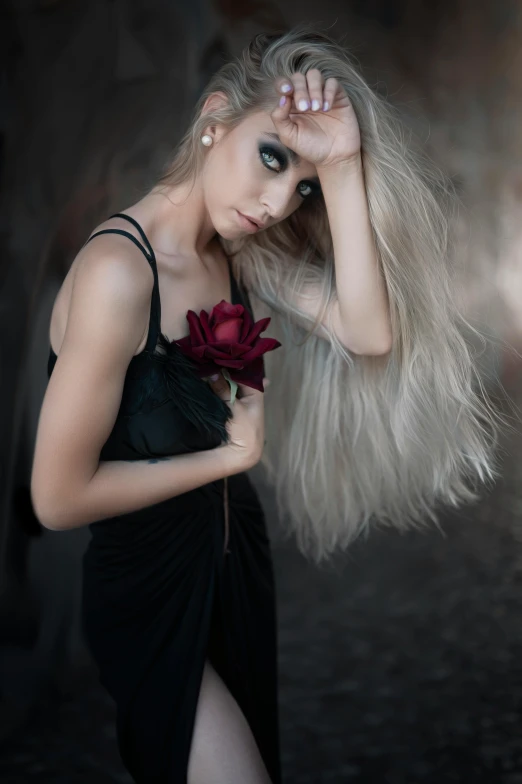 woman with long blond hair and makeup with flower in hand