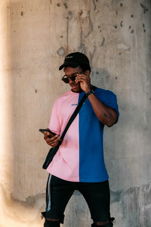 a man is standing in front of a cement wall using his phone