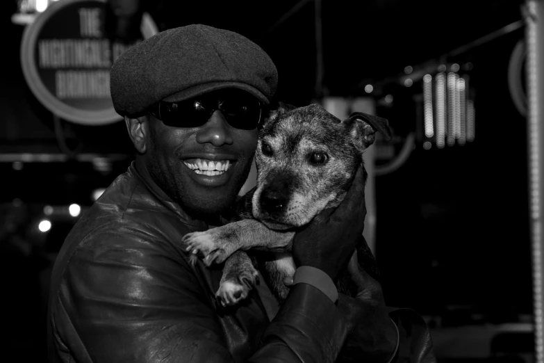 a man smiles and holds his dog as it looks up