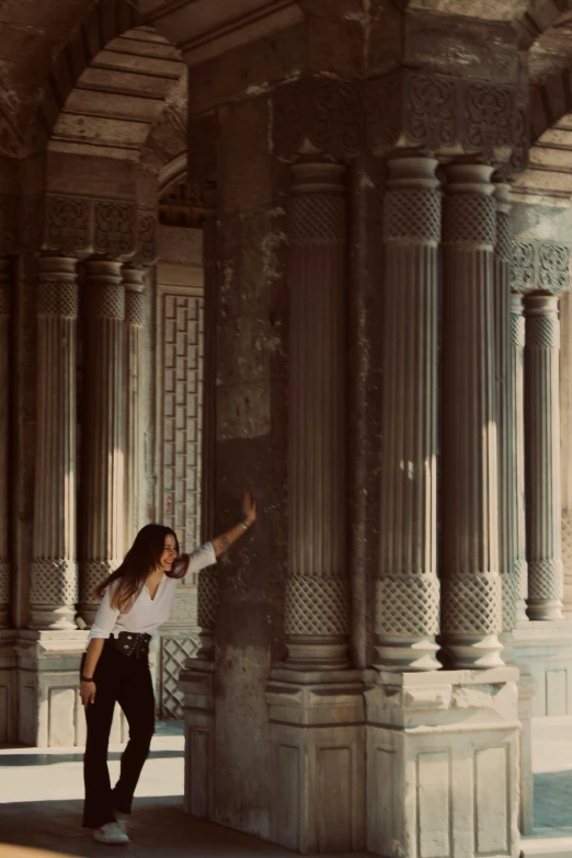 a woman is posing next to some columns