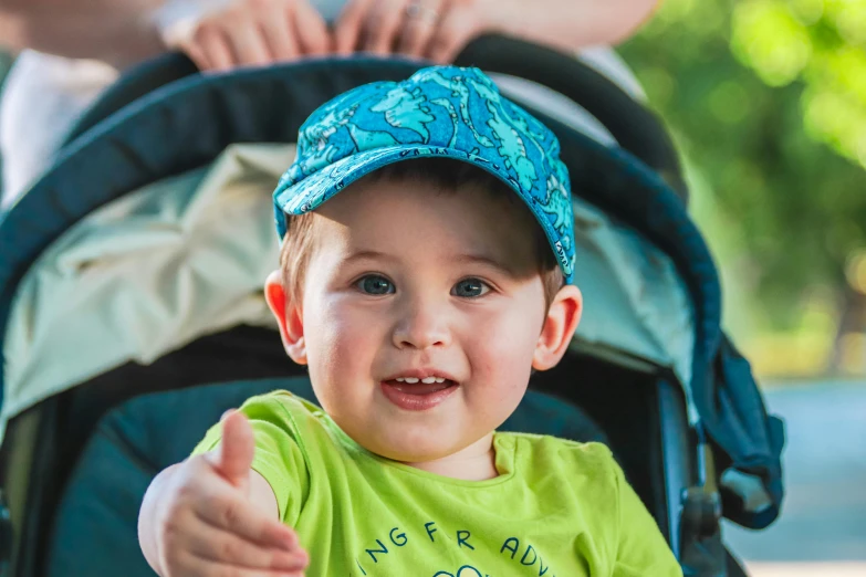 a small boy in a green shirt gives the thumbs up