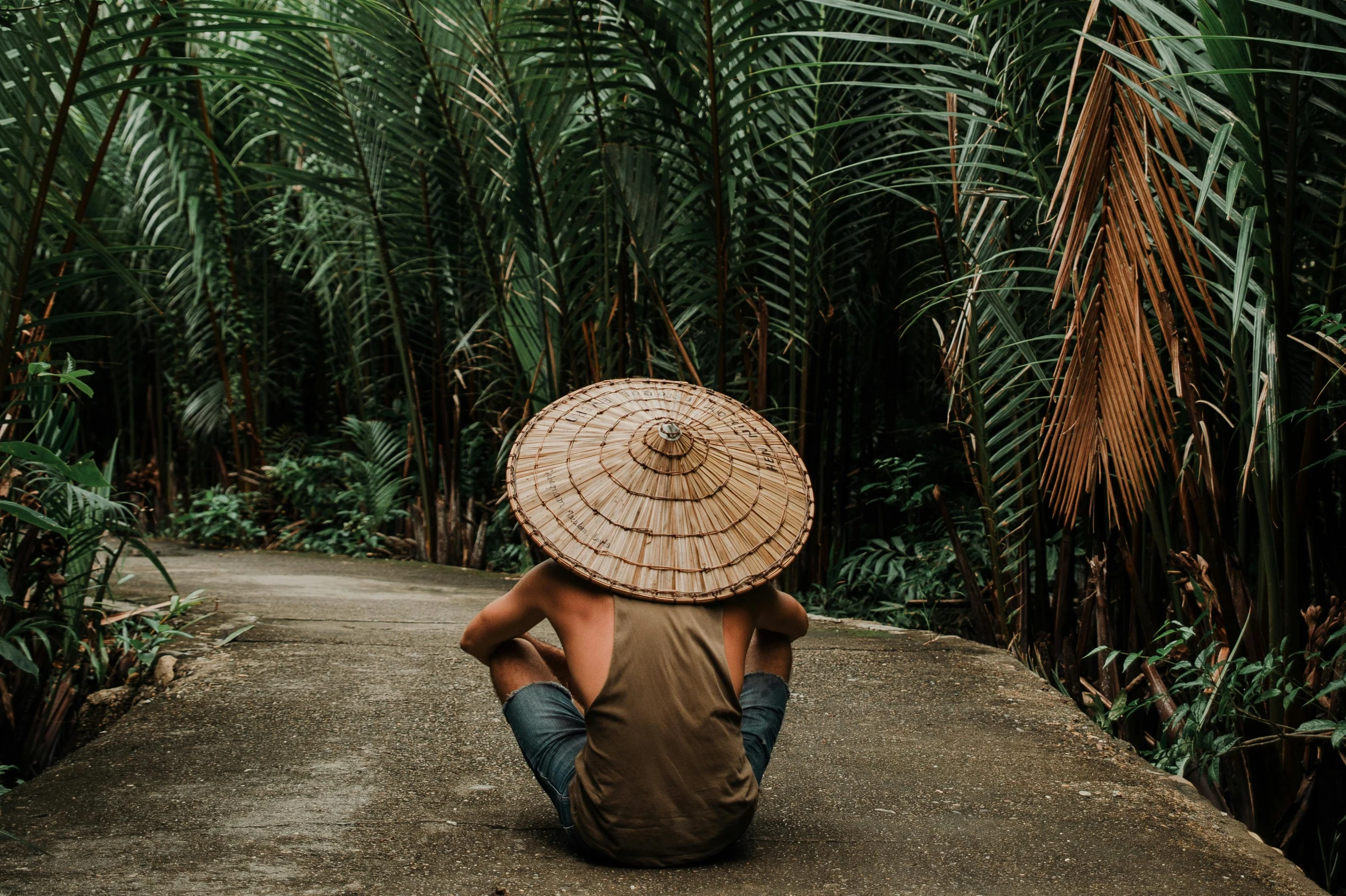 a person in a straw hat sits on the road