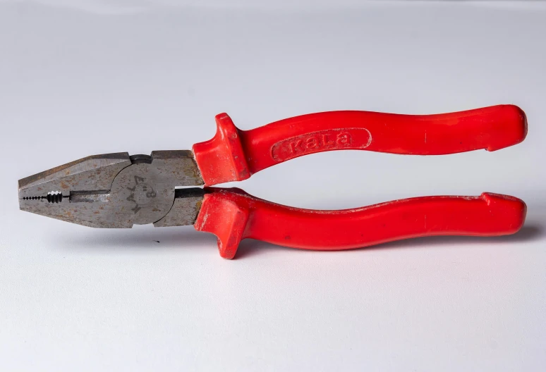 the red handles of two pliers on a white surface