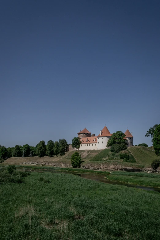 an old, well - kept castle on a hill overlooking a lake