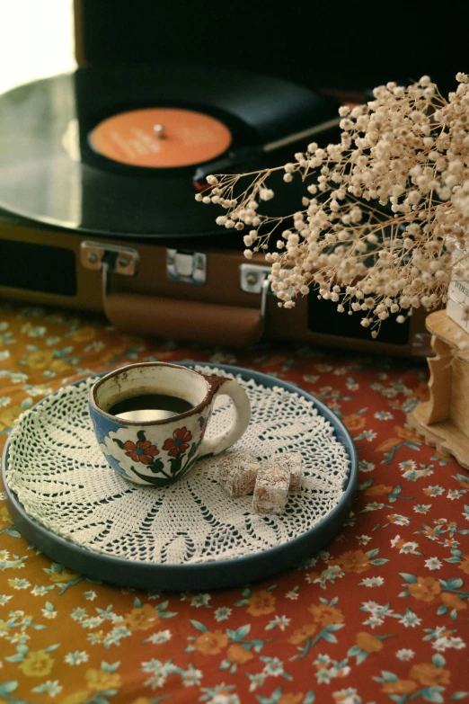 a tea cup next to a record player on a table