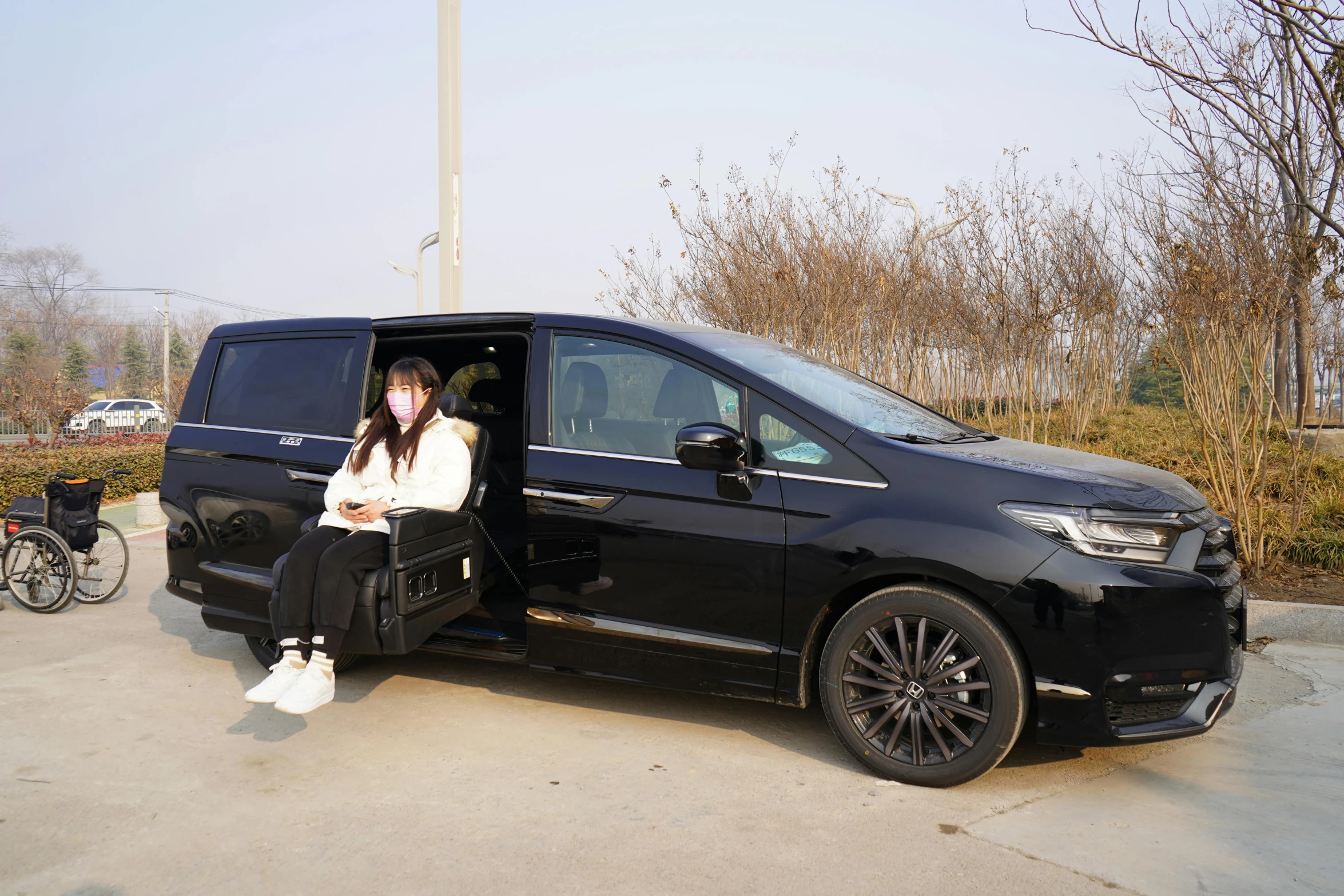 a woman sitting in an area near a black minivan