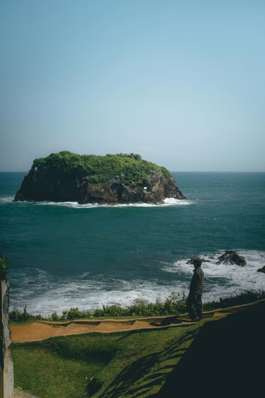 man standing on the beach looking over a cliff