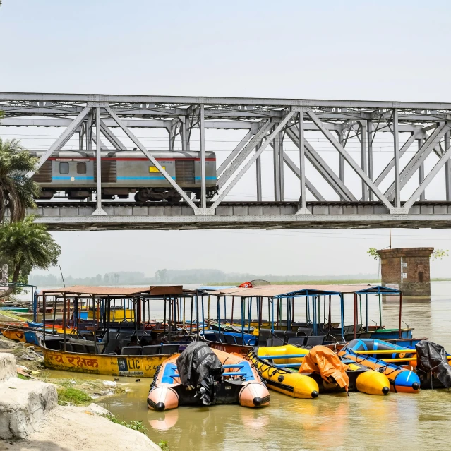 yellow rafts are parked in front of several boats under a bridge