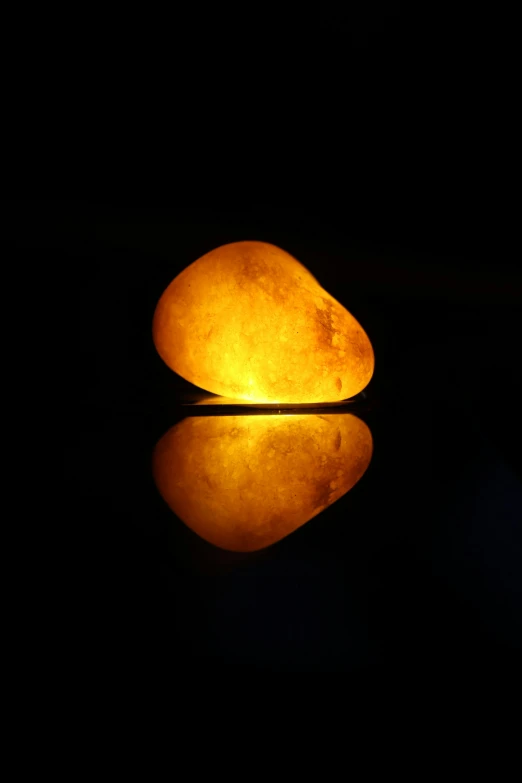 a light rock sitting on a surface in the dark