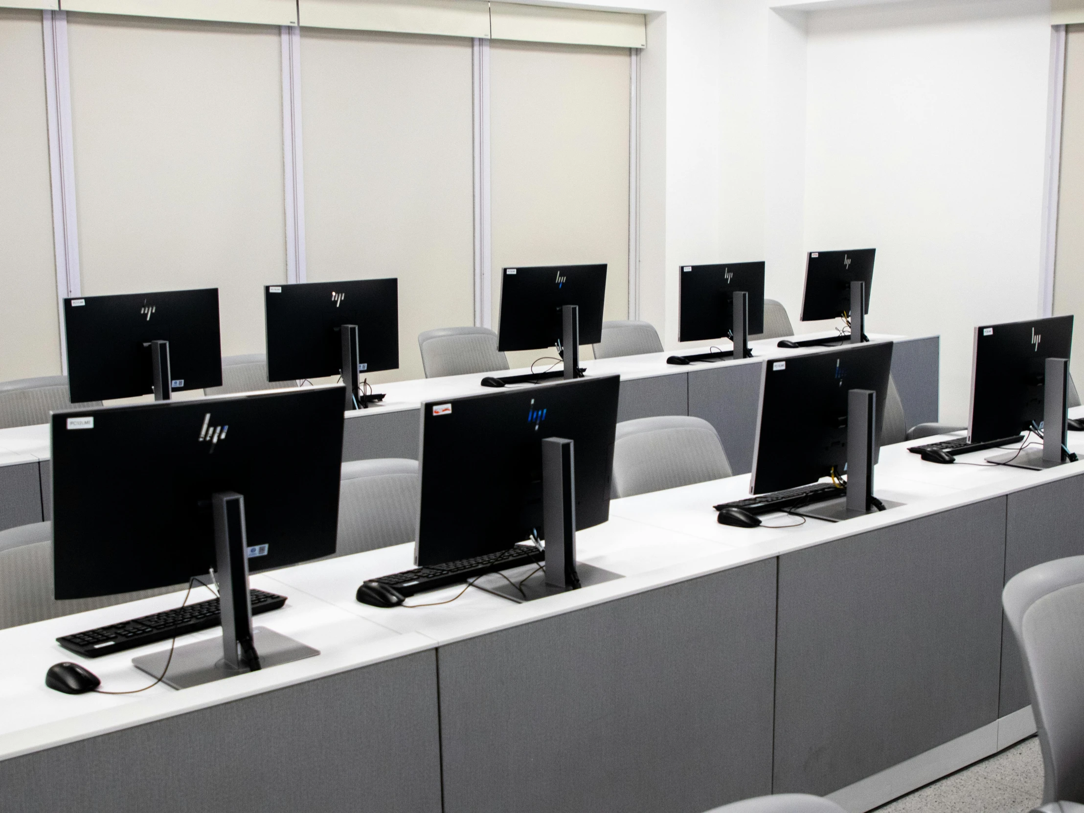 multiple rows of computers and monitors sitting on the edge of a long table