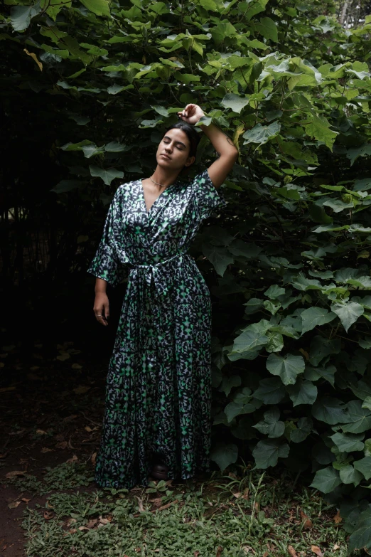 a beautiful young woman in a dress standing among trees