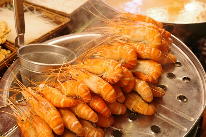 shrimp on a platter with a lot of sauce and a bowl in the background