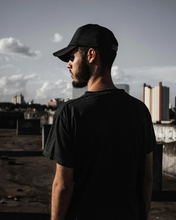 man with a black cap and beard standing next to a building