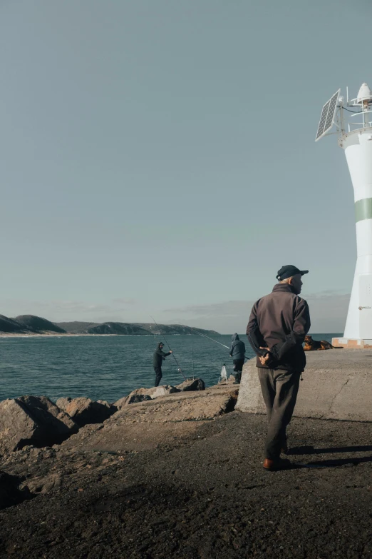 a man standing on the rocks next to a big light house