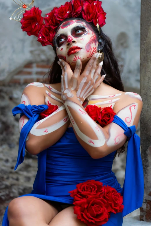 a woman dressed as a skeleton wearing flowery decorations and holding her hands out to her face