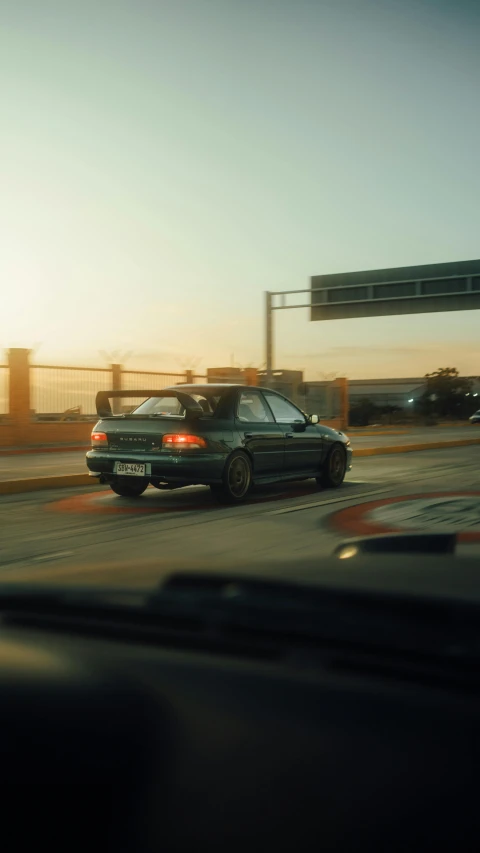 a black car with the hood open is parked at sunset