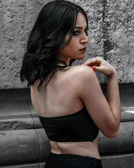 a woman in a bikini posing by a wall