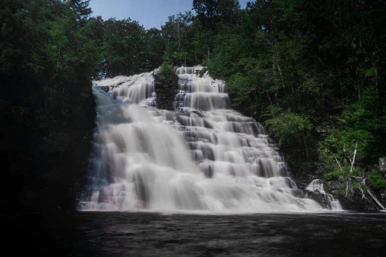 a waterfall has it's spray on water by the trees