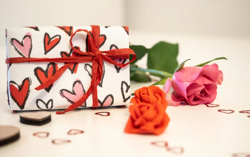 the gift box is adorned with hearts and red ribbon