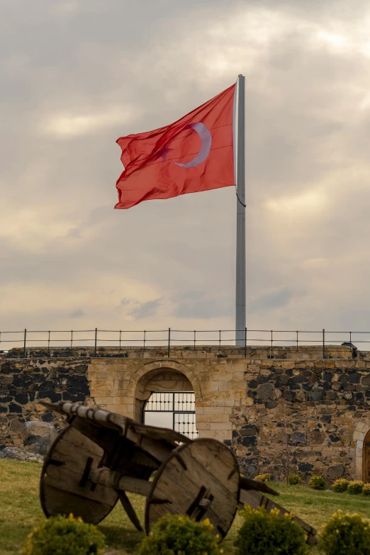 a flag flying next to two wagon wheels on display