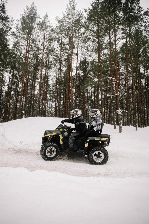 two people riding four wheelers through the snow