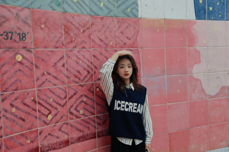 a woman is standing against a pink and blue wall