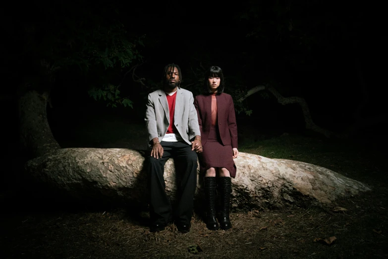 two people sit on top of a rock in the dark