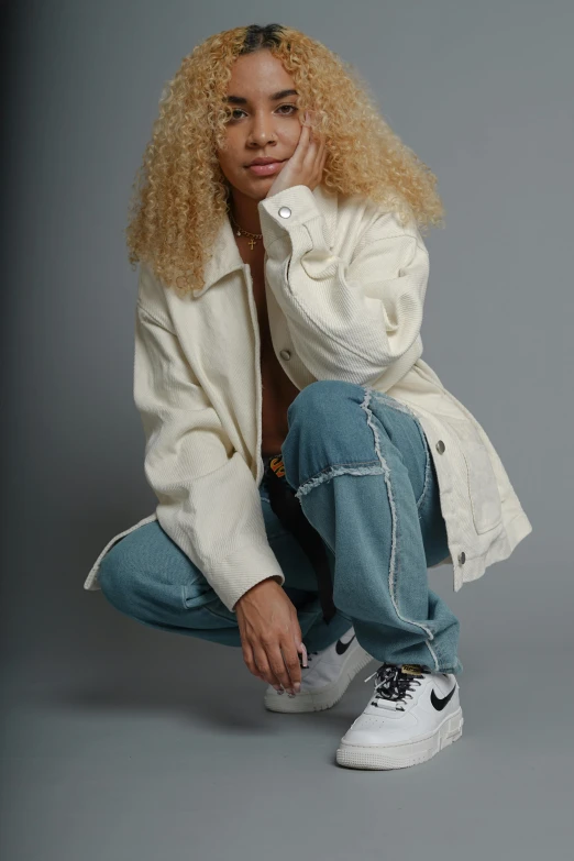 a woman is wearing denim pants and a white jacket