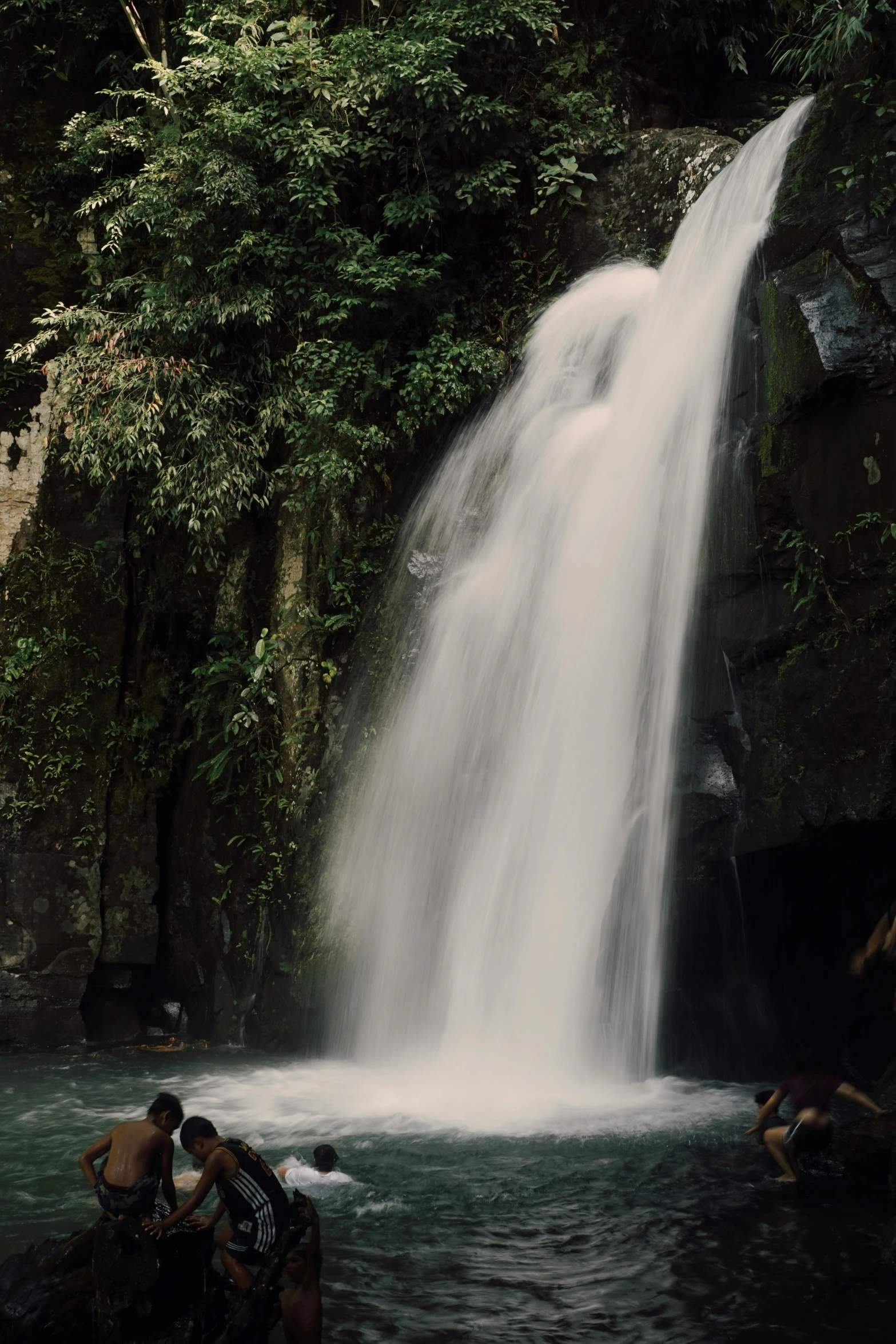 people taking a bath and bathing in front of a waterfall