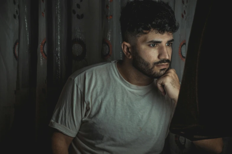 a young man standing next to a wall in a dark room