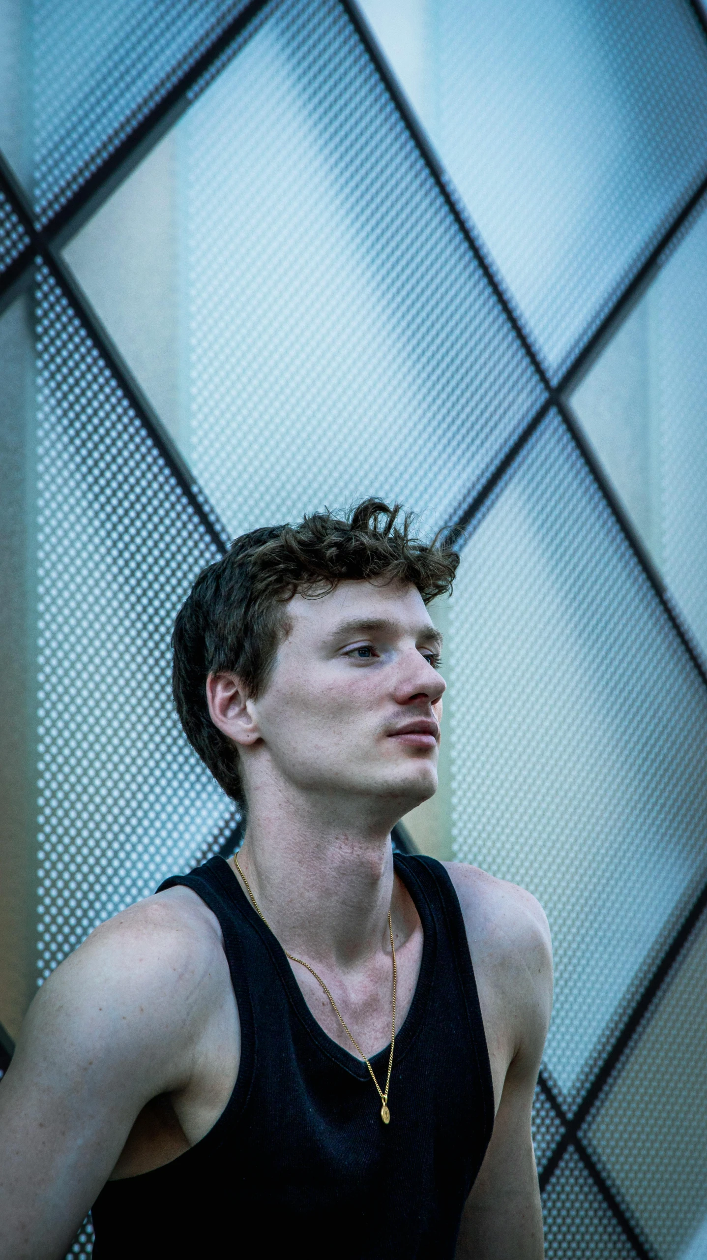 man in tank top standing against large glass wall