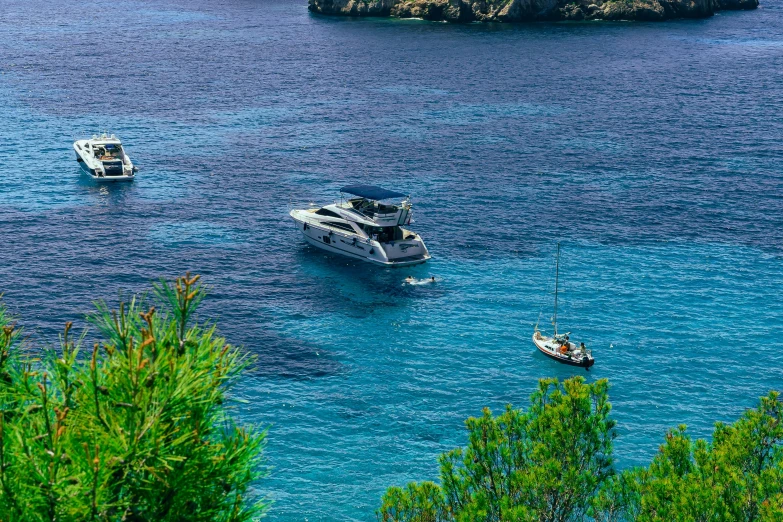 several boats floating in the ocean next to an island