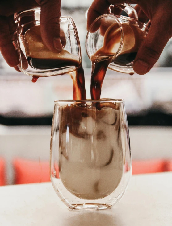 a pair of hands pour coffee into a glass