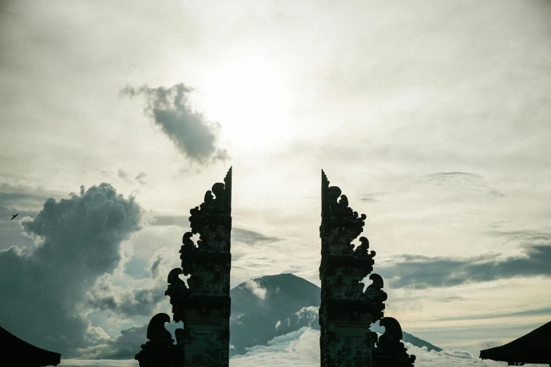 the silhouette of two stone towers on a cloudy day