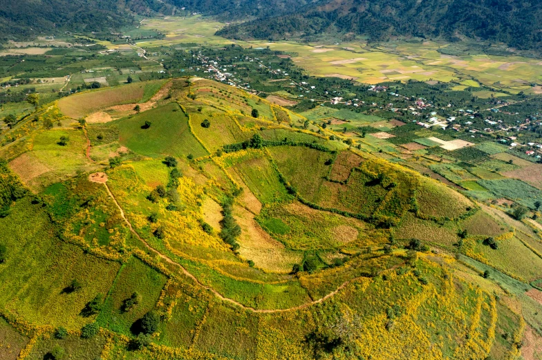 an aerial view of a small mountain town on top of a grassy hill