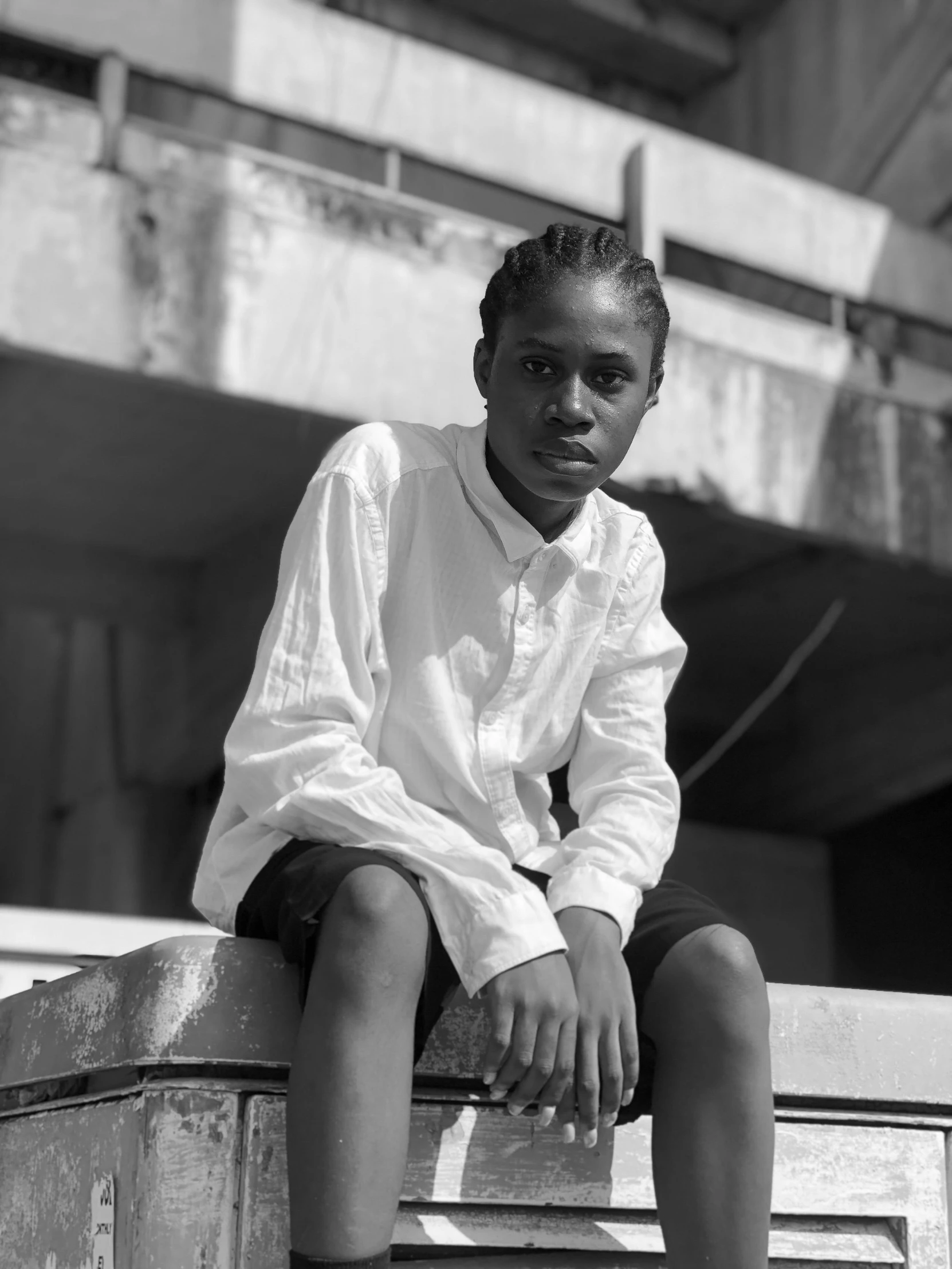 a little girl sitting on a ledge in a white shirt