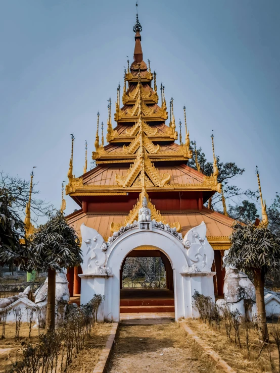 a very tall golden building sitting in the middle of some trees