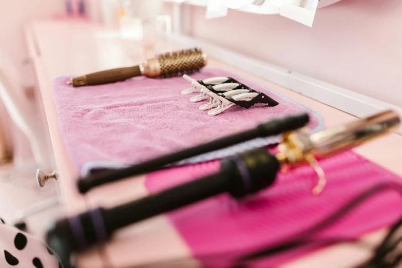 an assortment of different hair tools on pink towels