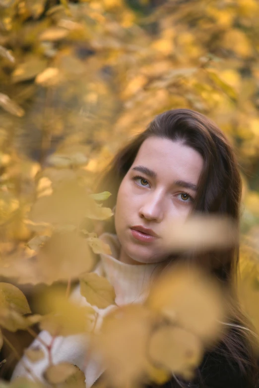 a woman poses as if looking out through the trees