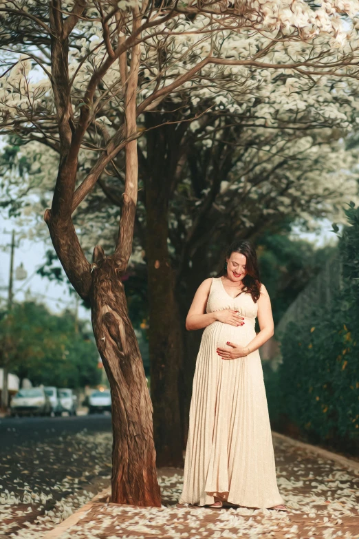 a woman with her hands in her pocket leaning against a tree