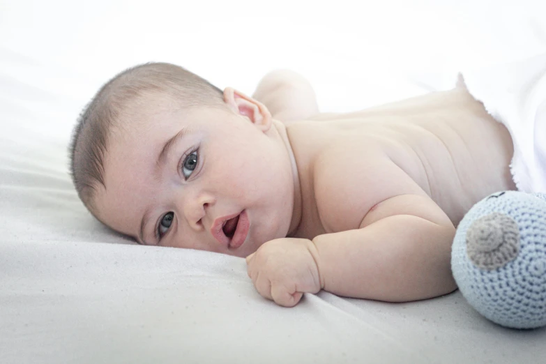 a baby laying down next to a toy