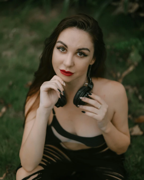 a woman sits on the grass, while holding her cell phone