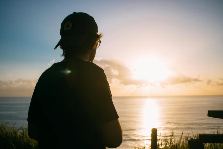 man looking out over the ocean at sun setting