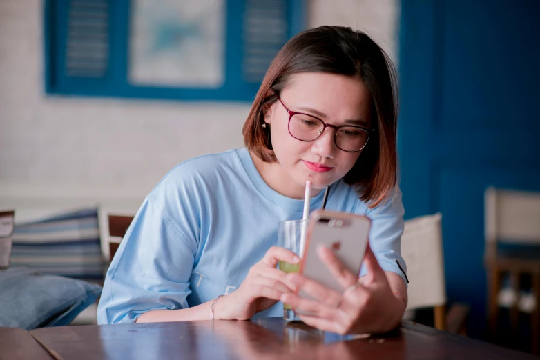 a woman sitting at a table using her cell phone