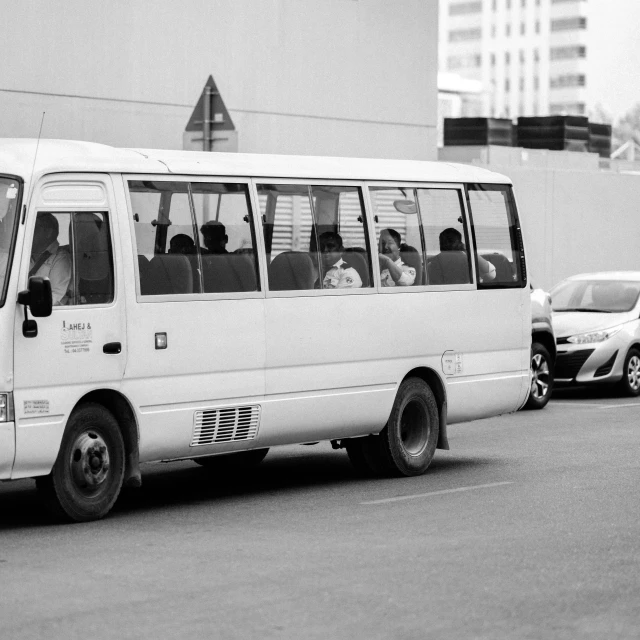 a long white van with passengers riding down a street