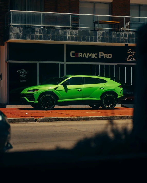 the green car is parked in front of the building